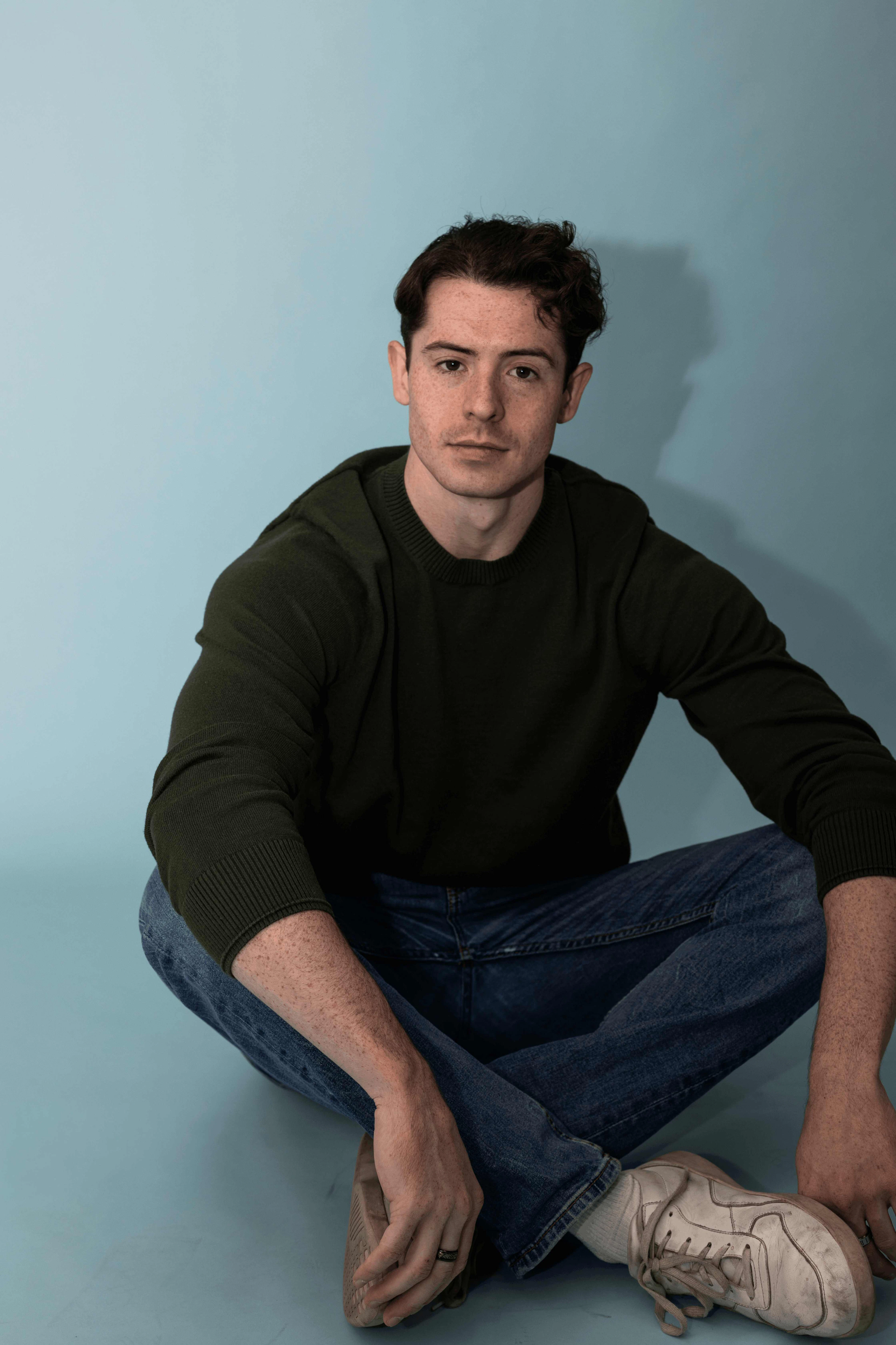 Maxwell Knowles seated portrait in green sweater